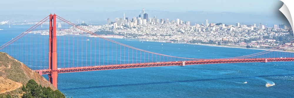 Panoramic photograph of the bright red Golden Gate Bridge with San Francisco in the background.