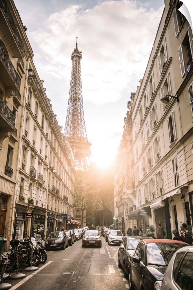 Photograph of a streetscape in Paris with the sun beaming through the Eiffel Tower in the background.