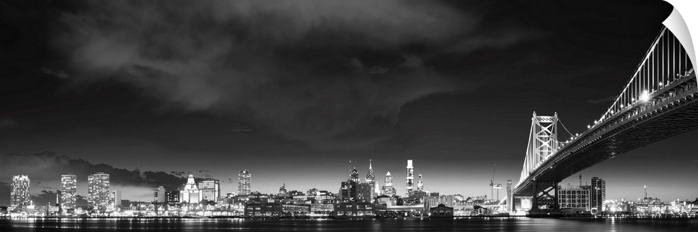 Panoramic photo of the Philadelphia city skyline at night, with the Benjamin Franklin Bridge on the right.