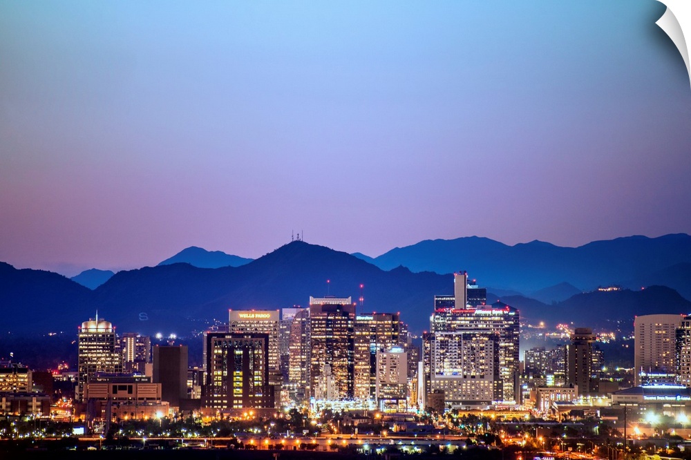 Photograph of a colorful sunset over the Phoenix, Arizona skyline with silhouetted mountains in the background.