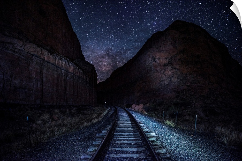 View of railroad tracks at night with a starry sky above near Arches National Park in Utah.