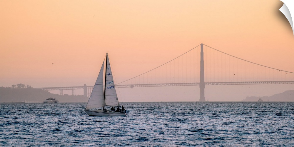 A lone sailboat floats in the pacific ocean with Golden Gate bridge in the background, San Francisco.