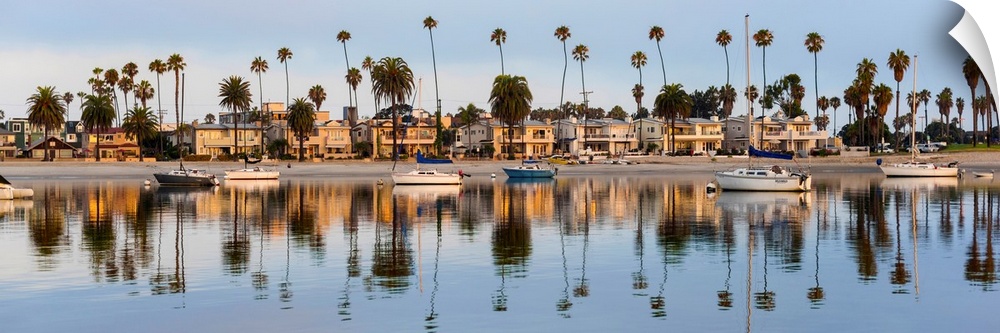 Panoramic photograph of beach houses, palm trees, and boats on the San Diego coast reflecting into the water.