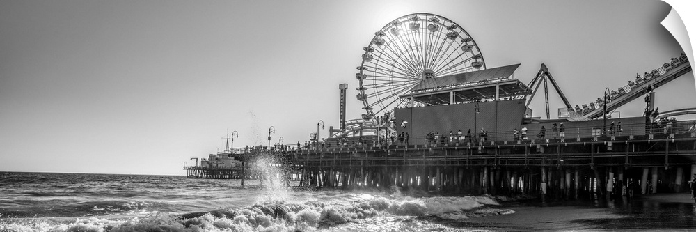 Panoramic photograph of the Santa Monica Pier in Los Angeles, California, with the sun setting right behind the Ferris Wheel.