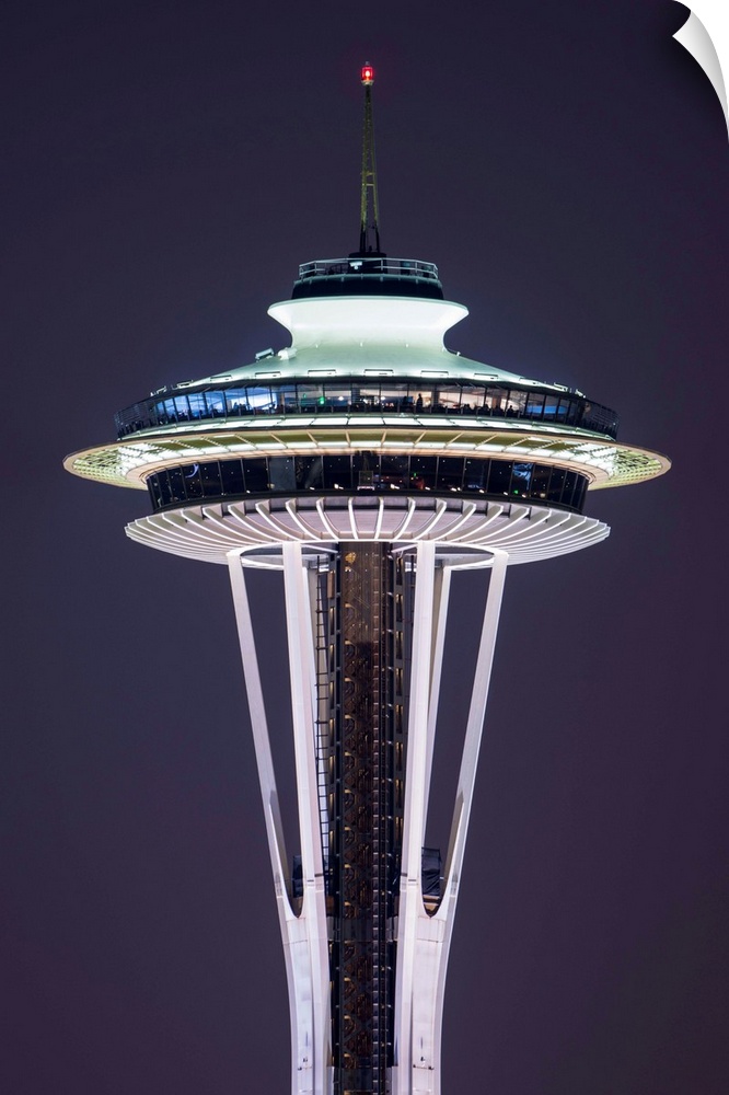 Photograph of the Seattle Space Needle lit up at night with dark purple skies in the background.