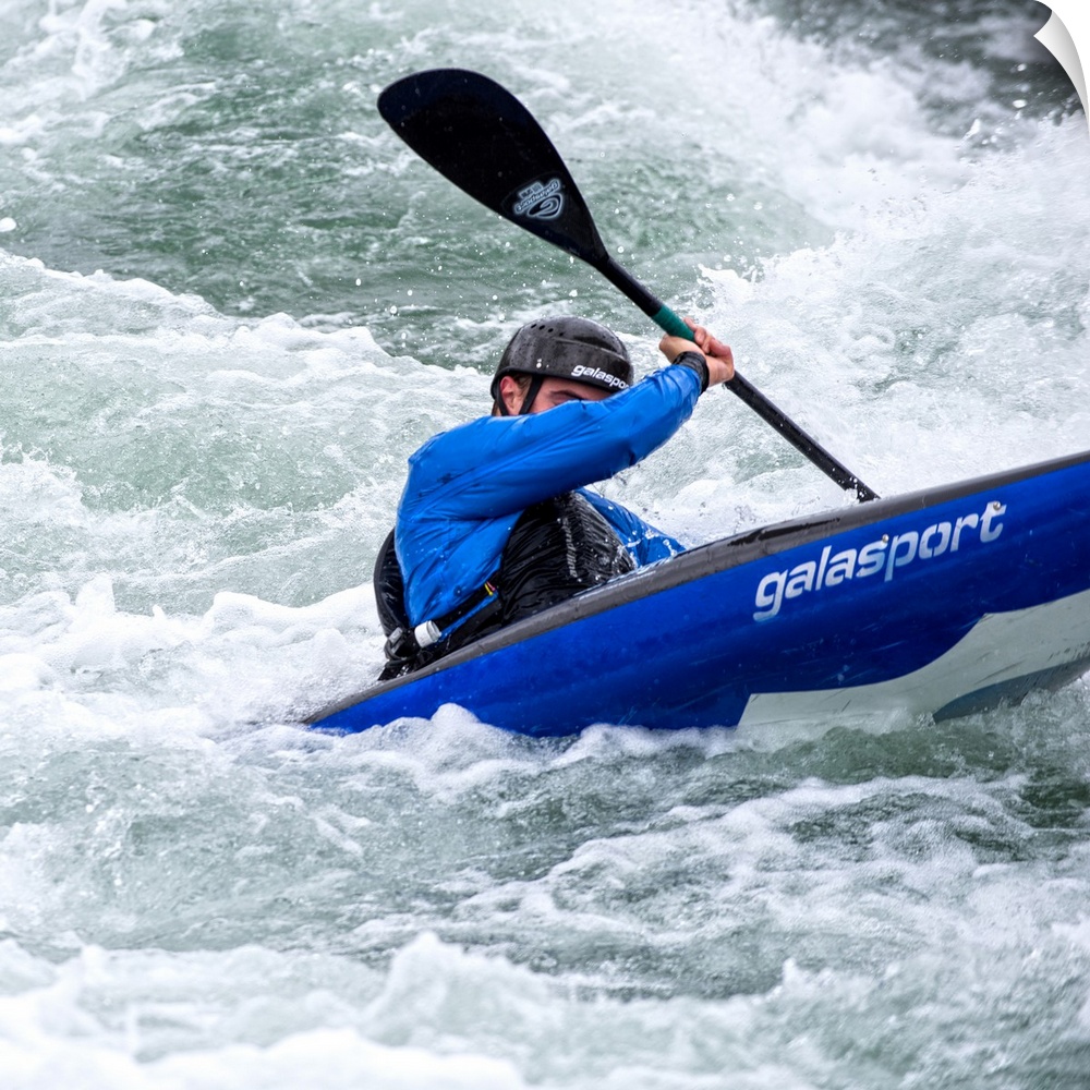 A person paddling in a kayak in whitewater rapids.