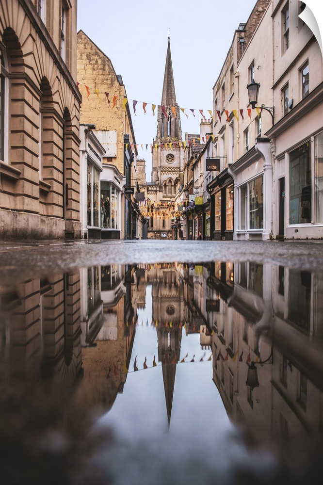 Photograph of St. Michael's Church reflecting into a puddle in the middle of a street in Bath, England.