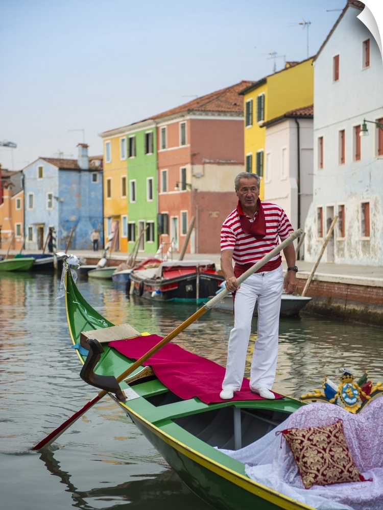 Photograph of a gondolier wearing a red and white striped shirt, rowing through a canal lined with vibrant facades.