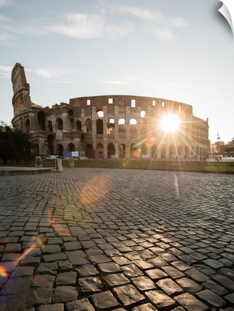 Photograph of the sun shining right though the middle of the Colosseum.