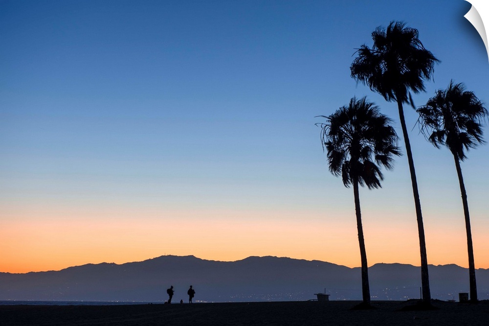 The sun sets on Venice beach with the San Gabriel mountains in the background.