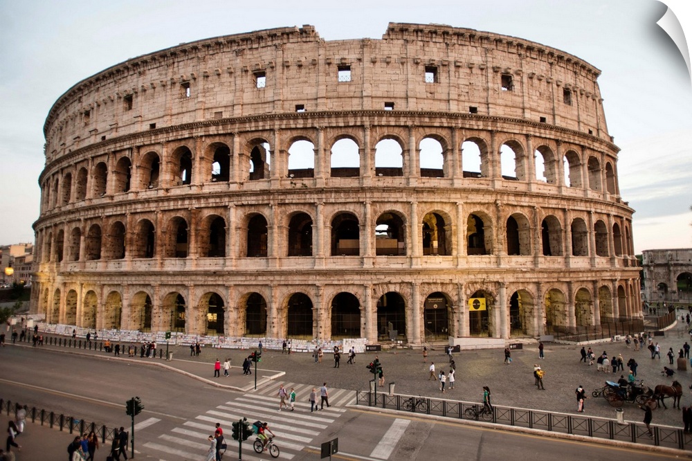 Photograph of the Colosseum from across the street with tourists surrounding the grounds.