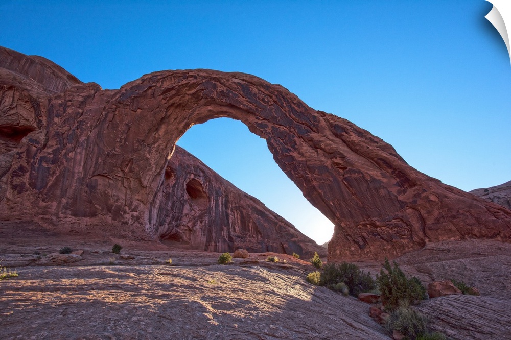 The sun setting behind the Corona Arch in Bootlegger Canyon, Moab, Arches National Park, Utah.