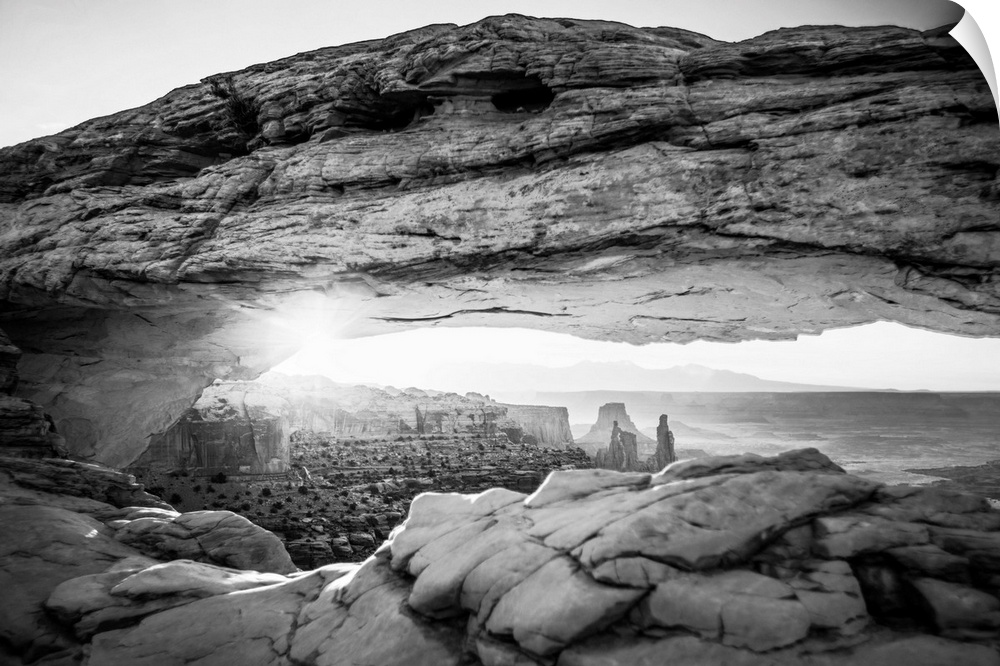 The underside of the Mesa Arch glowing bright orange with sunlight, with Buck Canyon in the distance, Canyonlands National...