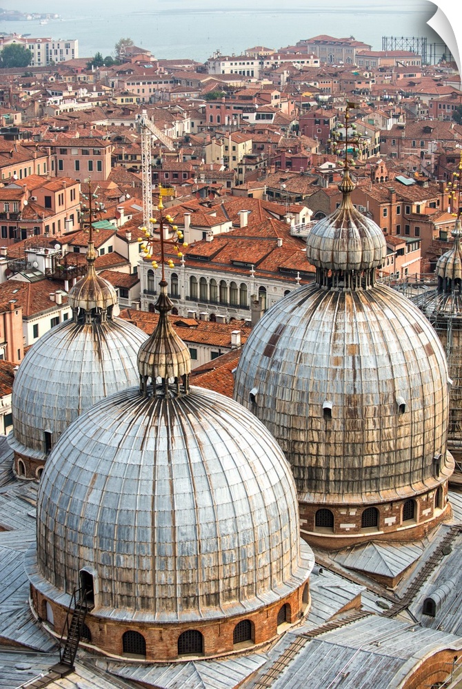 Aerial view of three domes of San Marco Basilica with Venice rooftops in the background.