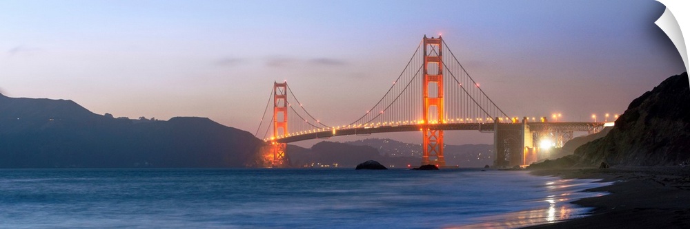 Panoramic photograph at twilight of the Golden Gate Bridge taken from the shore.