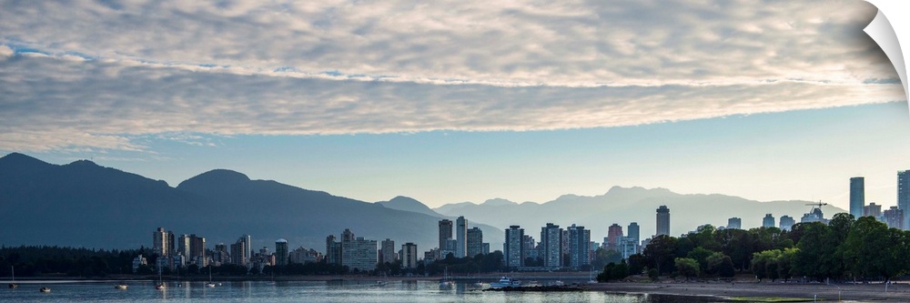 Panoramic photograph of the Vancouver, British Columbia, Canada skyline at sunset with silhouetted mountains in the backgr...