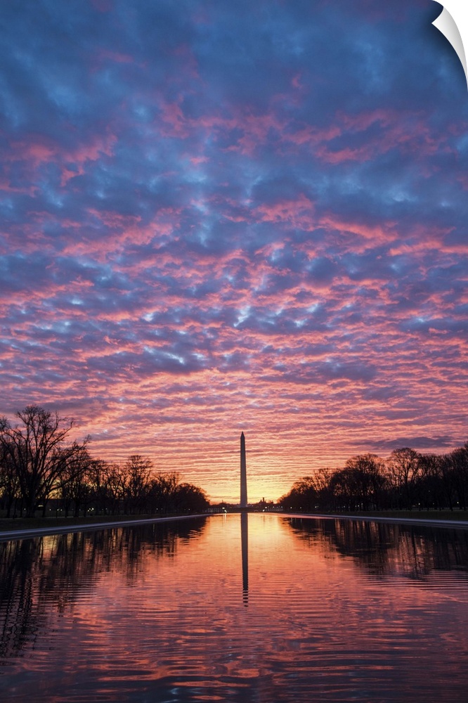 View from the Reflecting Pool of the Washington Monument under dramatic sunset clouds in Washington, DC.