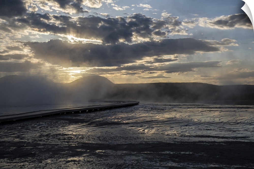 The sun rays peeking over hot springs at Yellowstone National Park.