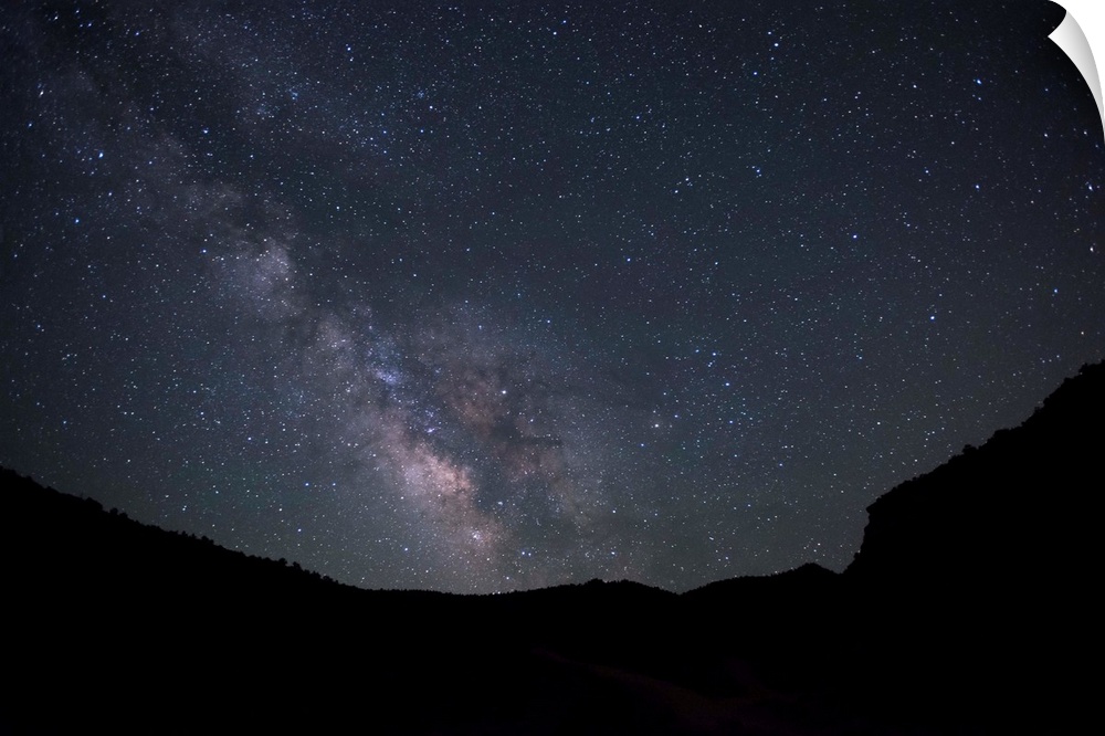 Silhouette photograph of Zion National Park at night time with a starry sky and the Milky Way above.