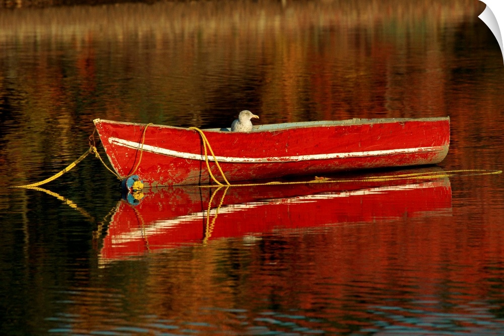 A moored old red boat and its mirror reflection on still waters.