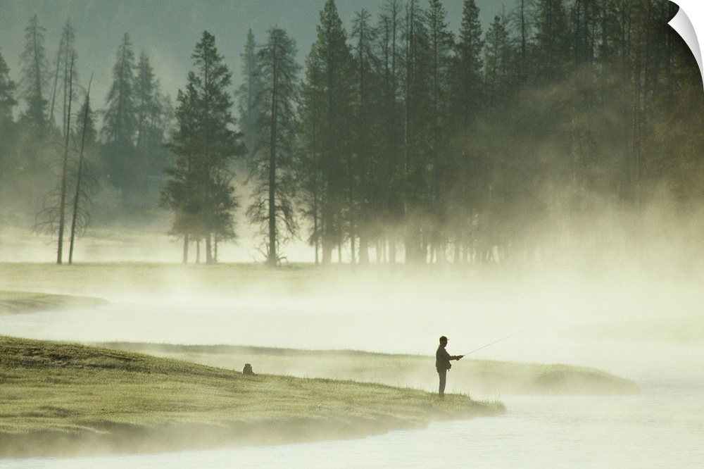 From the National Geographic Collection.  Photograph of a silhouette of a man fishing at lake's edge in the morning fog.  ...
