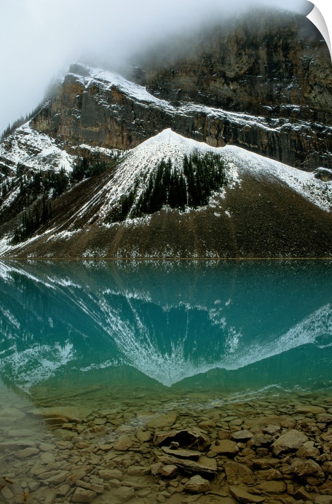 Fog has lifted from Lake Louise and reflections of the snow-capped mountains ar e visible in this glacial lake.