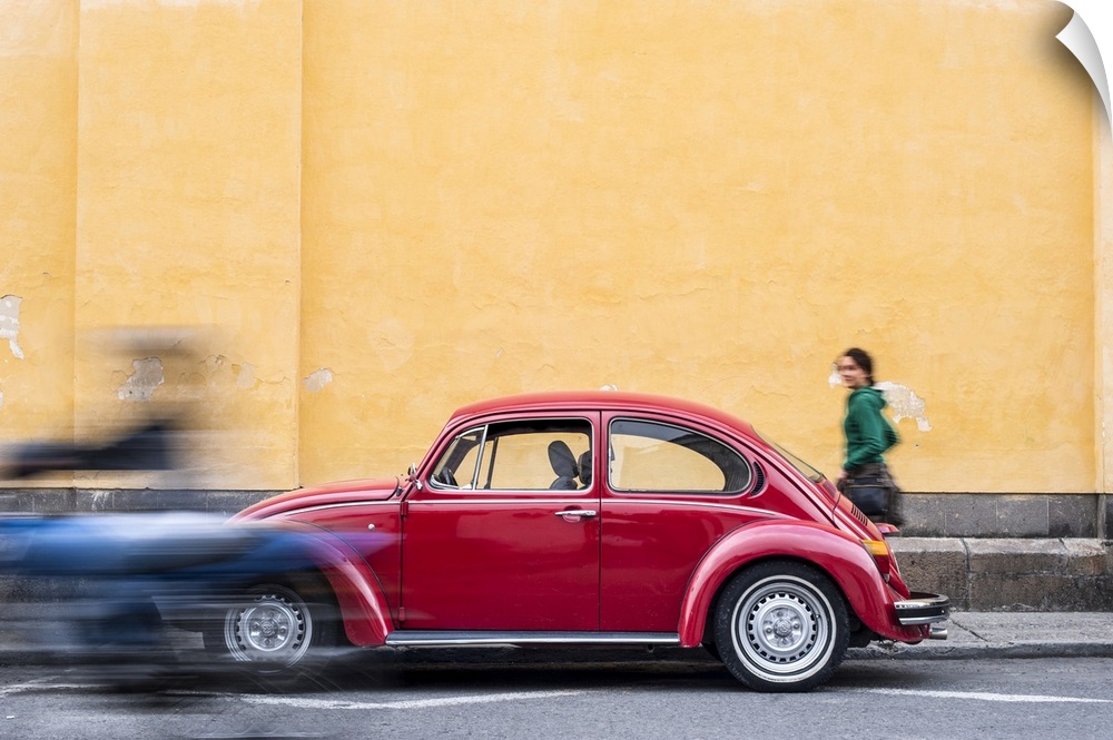 A woman walking past a red VW Beetle in the colourful streets of Popayan, Colombia, South America