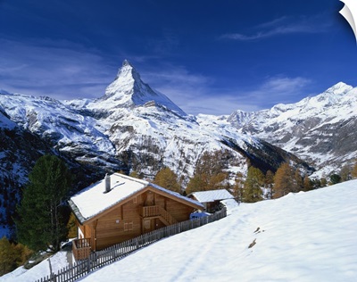 Chalets in a snowy landscape with the Matterhorn peak, Swiss Alps, Switzerland