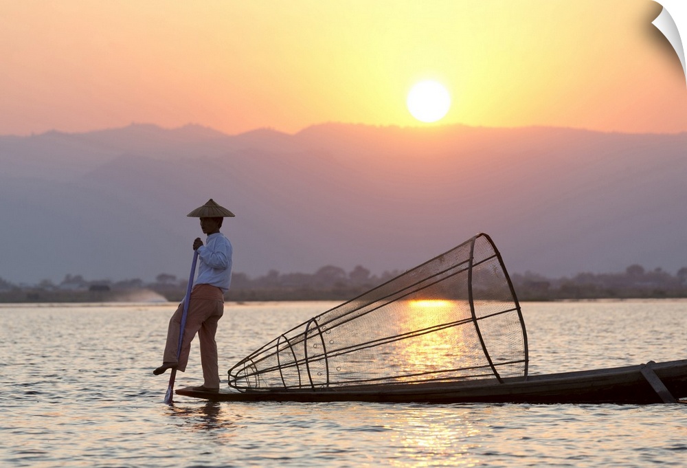 Intha leg rowing fishermen at sunset on Inle Lake who row traditional wooden boats using their leg and fish using nets str...