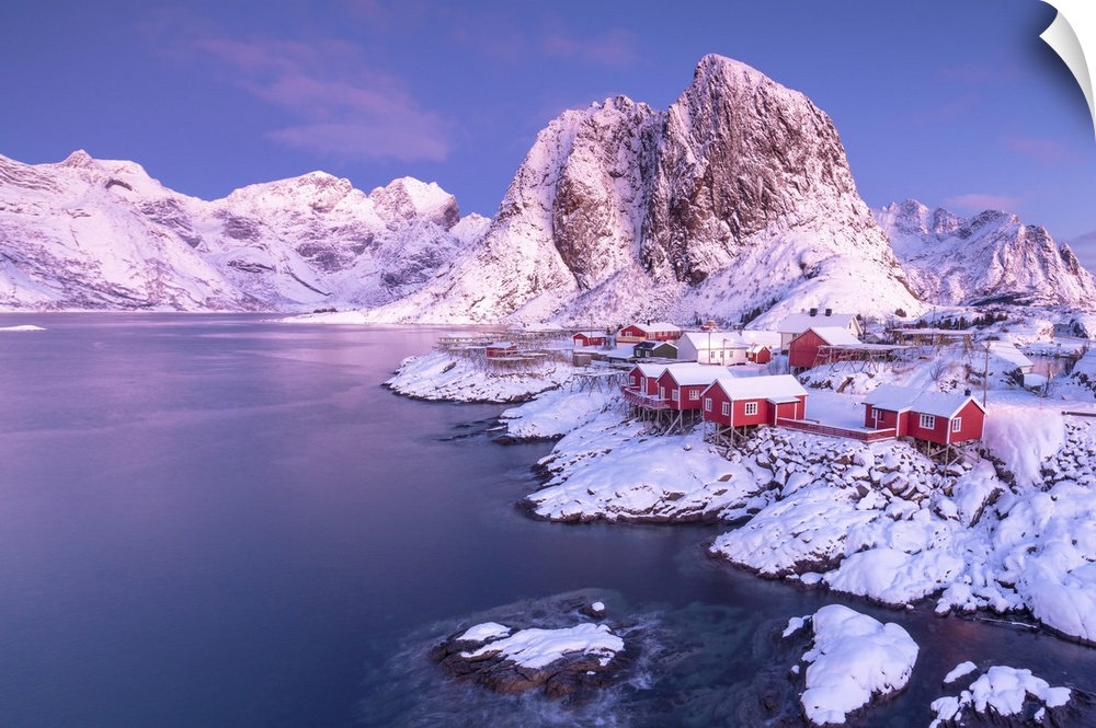 Pink sunrise on snowy peaks surrounded by the frozen sea around the village of Hamnoy, Nordland, Lofoten Islands, Arctic, ...