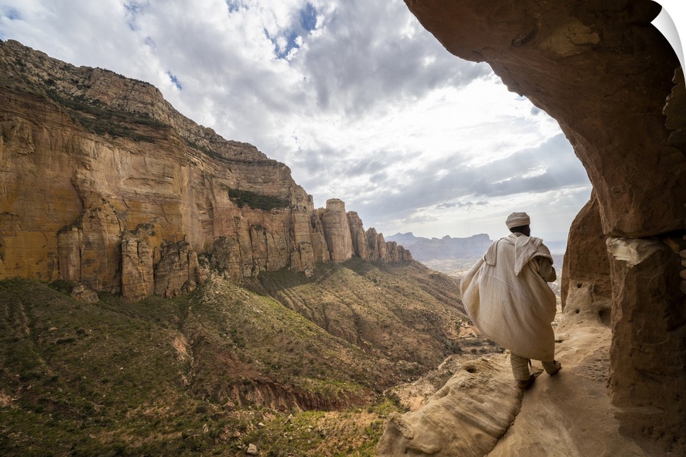 Rear view of priest walking on access trail to the rock-hewn Abuna Yemata Guh church, Gheralta Mountains, Tigray region, E...