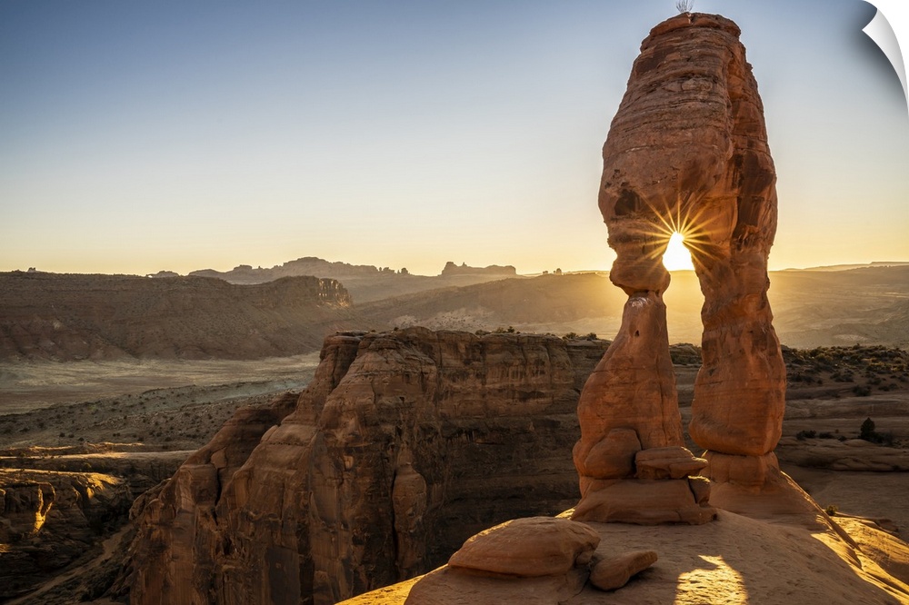 Setting sun through Delicate Arch with sunburst, Arches National Park, Utah, United States of America, North America