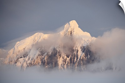 Snow covered mountain at sunset, generating fog cover, Wiencke Island, Antarctica