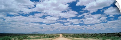 Straight gravel road cutting across grassy plain near Windhoek, Namibia