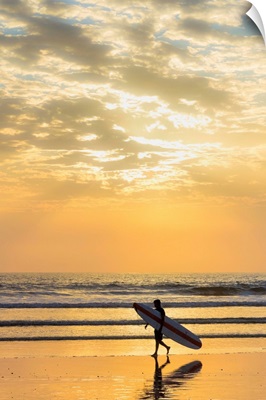 Surfer with long board at sunset on popular Playa Guiones surf beach, Costa Rica