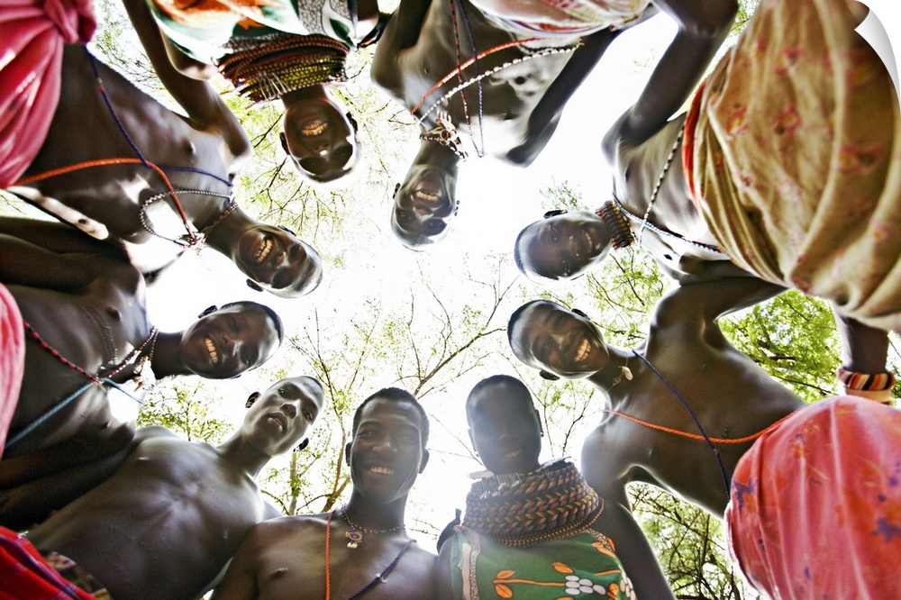 Photograph of natives in a circle looking down at camera with forest as back drop.