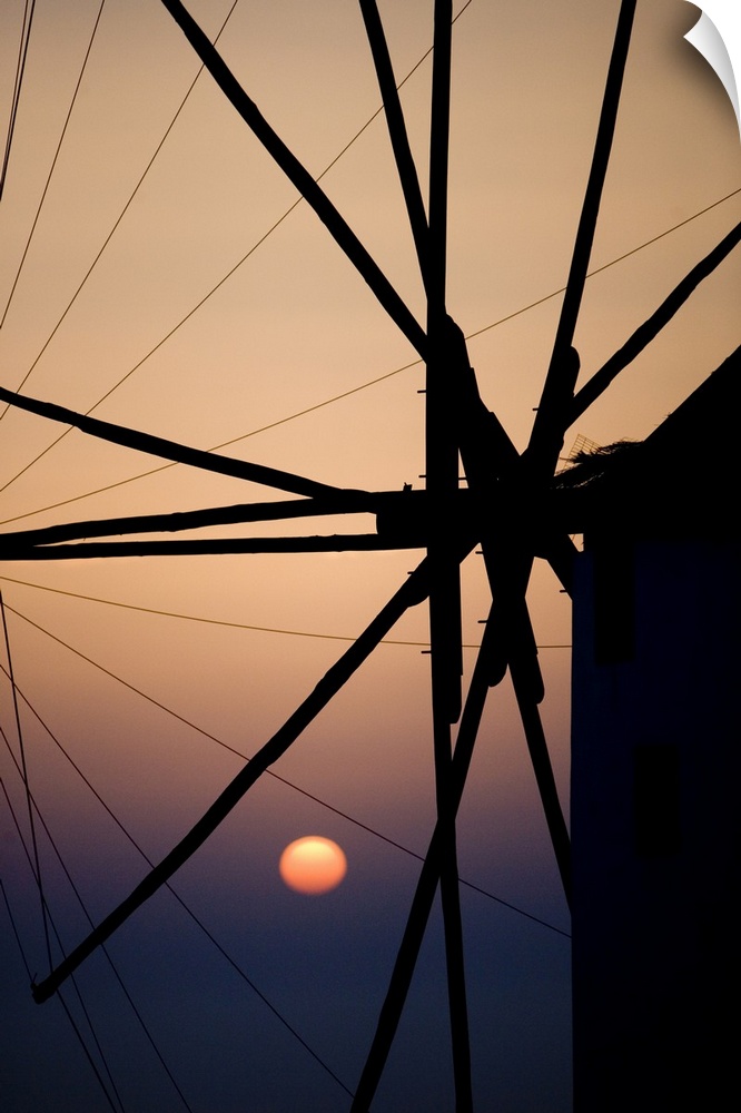 Giant, vertical, close up photograph of the spokes of a windmill at sunset, in Mykonos, Greece.