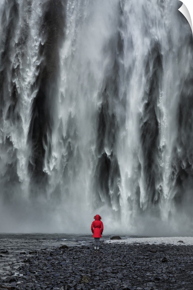 Woman staring into Skogafoss waterfall in Iceland.