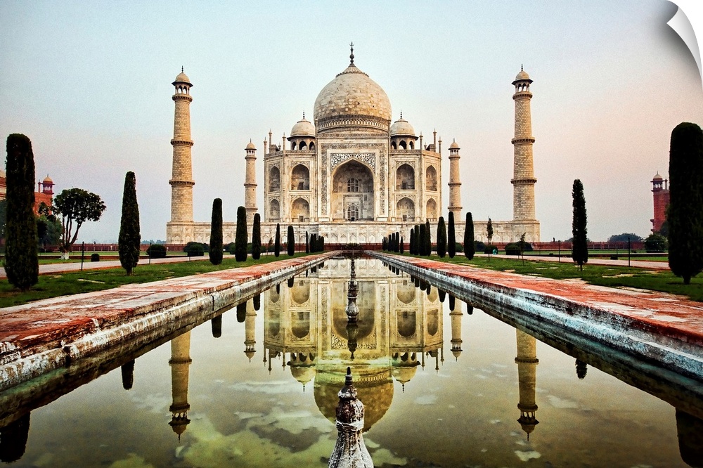 Photograph of an ornate marble mausoleum.  A reflection pool is located in front lined with tall shaped trees.