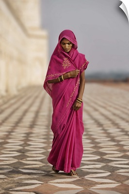 Indian woman in red dress walking by the Taj Mahal, Agra, India