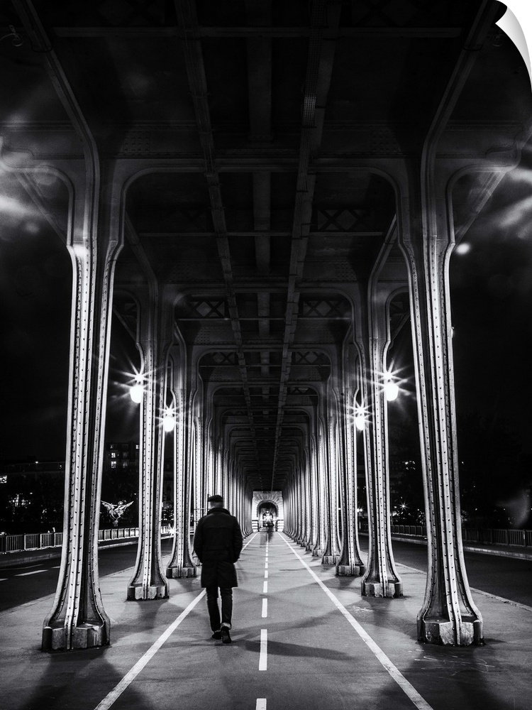 Black and white photograph of a man walking under an overpass in Paris.