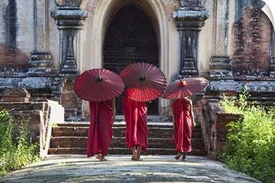 Monks with parasols by monastery in Pagan, Burma