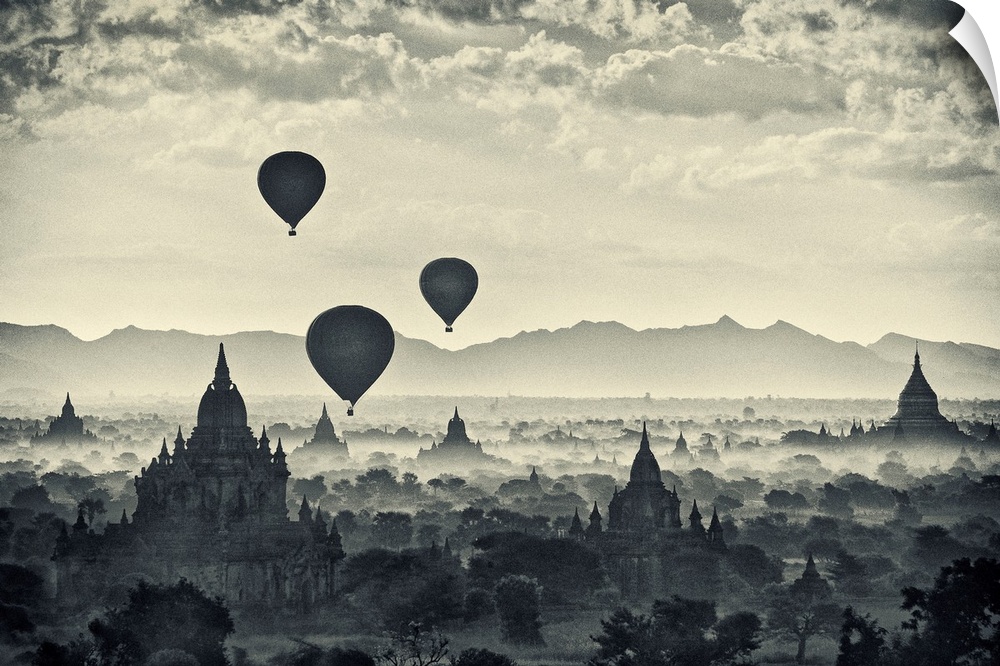 This monochromatic photograph shows a landscape of hot air balloons rising above the stupas of an ancient city.
