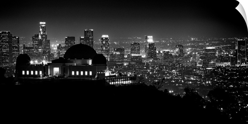 Large monochromatic photograph displays the busy skyline of a famous California city at nighttime.  The speckled lights co...