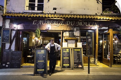 Waiter in front of a Paris cafe at night