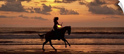 Woman riding a horse on the beach at sunset in Costa Rica