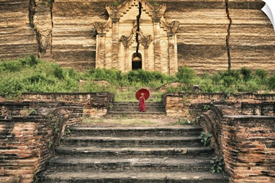 Young Burmese monk boy walking with parasol by his monastery