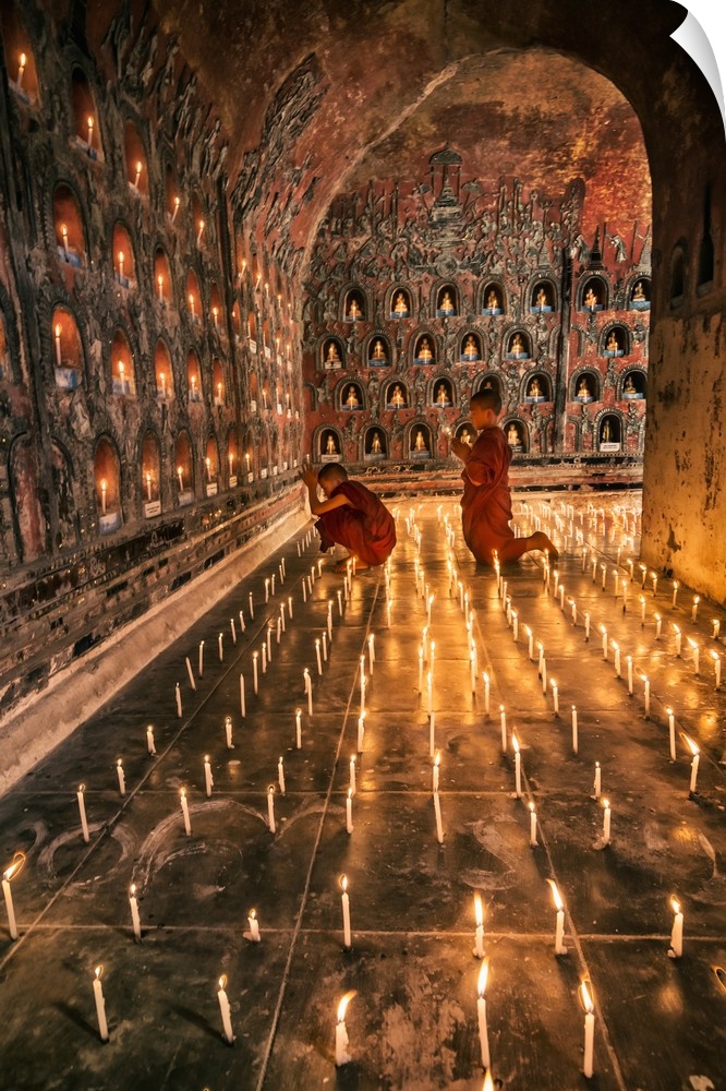 Young monk praying with candles in his monastery in Myanmar.