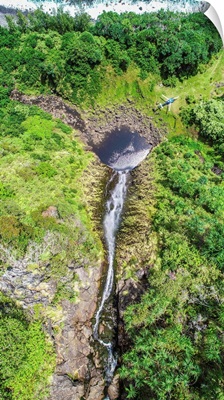 A Blue Hawaiian Helicopter Sets Down On A Remote Waterfall Near Hawaii's Shoreline