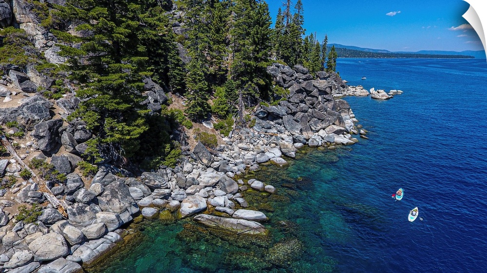 A pair of stand-up paddlers explore beautiful lake Tahoe. Location: Lake Tahoe, California.